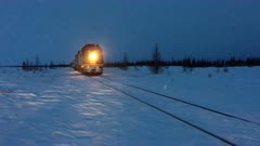 Train passing by in a desolate snow covered tundra of Canada, with people waiting to go onboard.