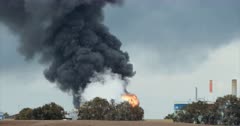 Environmental pollution - huge fire accident in an oil refinery with thick black smoke rising