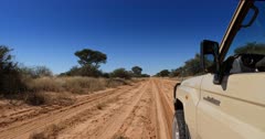 A tracking shot of a safari vehicle driving on rough dirt roads.