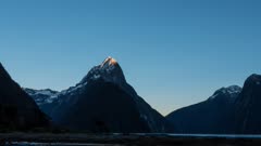 a time lapse of the sun rising on the summit of mitre peak in milford sound