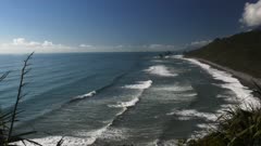 surf rolls in onto a beach on the west coast of new zealand's south island