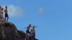 a young boy cools off a hot hawaiian summer day by jumping off the large rock at wiamea bay