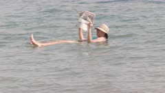 a woman reads a newspaper while floating in israel's dead sea
