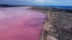 an aerial view, flying forward and to the south, of the pink water of hutt lagoon in western australia