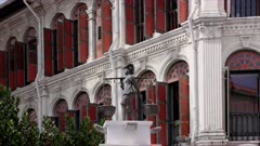 a zoom in on a sculpture of a coolie carrying baskets on a pole at smith street in chinatown, singapore