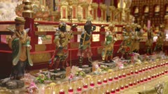 several small statuettes of buddhist deities and burning candles inside buddha tooth relic temple and museum in singapore