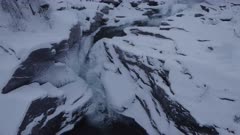 Aerial view of river and waterfall with pancake ice, lifting up and tilt