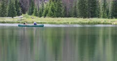 Young couple in canoe mountain lake. Friends enjoy nature. Scenic high mountain lake used for recreation, canoe and fishing. Campgrounds on shore. Couples and families enjoy the great outdoors and nature. Pine and aspen forest. Calm and relaxing pleasure. 4K HD video footage. Despain Rekindle Photo. 1228