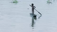 A child paddles a traditional canoe in a scene that could be hundreds of years old. Unchanged culture.