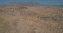 Aerial Drone Shot over Ocotillo Wells Bad Lands, flying over ridges and valleys, Mountains in the background