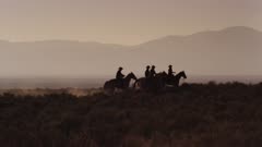 A group of 4 cowboys mosey from camera left to camera right