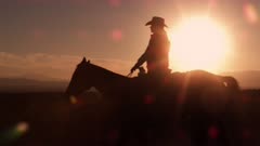 Slow motion shot of cowboy galloping in front of sunrise.