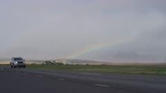 Icelandic horses in field, rainbow along the highway