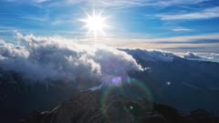 Winter bright sun in a blue sky over a mountain ridge with thick clouds