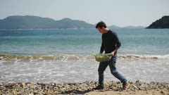 Environmental activist collecting plastic on a beach clean up due to climate emergency and ocean destruction, Hong Kong