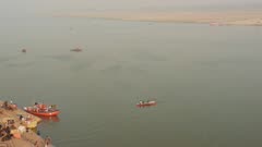 Orange Boats Sailing On The Trans-Boundary River Of Ganges Located In Varanasi, Uttar Pradesh, India. -wide shot