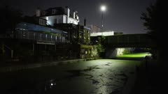 Moody night view of canal and buildings with bright green algae on water
