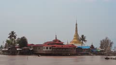Traditional buildings near the shoreline of Inle Lake, Myanmar, with canoe passing by
