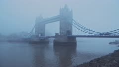 Tower Bridge with red London bus in foggy and misty atmospheric and moody weather conditions on Coronavirus Covid-19 lockdown day one on a blue cool morning, England, UK