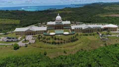 Aerial shot of Palauan capitol building flying from behind building and over with open ocean in the background