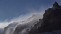 Snow mist blowing off rock cliffs and glacier headwall of mountains in Antarctic Dry Valleys