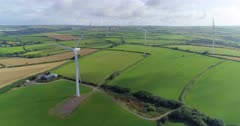 Rotating panning aerial shot of wind turbines revealing large numbers in the distance with large wind farm in the UK