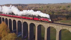 Aerial shot of red steam locomotive &quot;Duchess of Sutherland&quot; crossing a viaduct in the UK