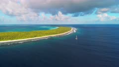 Aerial shot of remote atoll and sailing yacht near shore