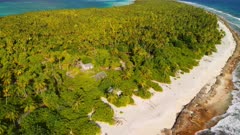 Aerial shot travelling towards remote atoll and abandoned village