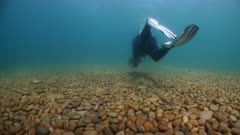 SCUBA Diver swims over seabed in temperate ocean. UK