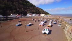  Aerial shot flying towards and over stranded fishing boats and harbour at very low tide, Minehead, Somerset, UK