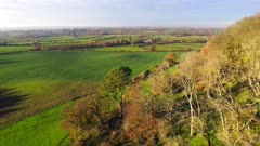 High wide shot flying over ramparts of Cadbury Iron age hill fort, Somerset. UK on cold winter afternoon