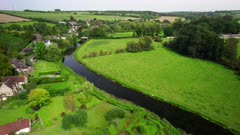 Aerial shot descending towards the River Avon as it flows through a small village in Wiltshire, UK
