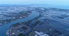 Drone footage of the southern part of Kampot, Cambodia. The camera is facing the sea where the Prek Kampong river is going into and is heading away from it following the river. You can see the salt fields around it.