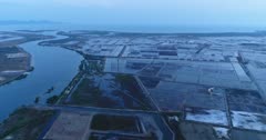 Drone footage of the southern part of Kampot, Cambodia. The camera is facing the sea where the Prek Kampong river is going into and is heading away from it following the river. You can see the huge salt field area around it.
