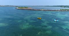 Drone footage of a boat towing an flying inflatable water sled (or flying fish) over the shallow reefs in the south of Serangan island. The camera is turning around a boat with its flying inflatable water sled stopped getting ready for the next ride.