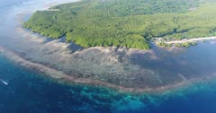 Drone footage of the mangroves and the shallow reef of the north-eastern part of Lembongan island at sunrise. The camera is facing the island with its huge mangrove area, shallow reefs and turquoise water and is tilting down going towards the reef.