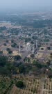 Vertical drone footage of the Marble Mughal mausoleum Bibi Ka Maqbara in Aurangabad, Maharashtra, India, with its huge garden around and some hills in the background. The camera is turning around the south side of the monument.