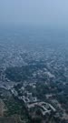 Vertical drone footage of the surroundings of Aurangabad city, Maharashtra, India, with its low buildings mostly white, the Marble Mughal mausoleum Bibi Ka Maqbara and some hills in the background. The camera is doing a full 360 degrees panning of the area around Aurangabad.