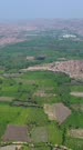 Vertical drone footage of the countryside near Hampi, Karnataka, India, with its rocky landscape, the granite like boulders forming hills with fields in between, the Malyavanta Raghunatha temple and the Tungabhadra river in the background. The camera is doing a full 360 degrees panning of the area.