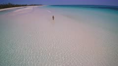 Girl in bikini walking on pristine beach paradise drone shot 4K