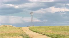 Windmill pumping water for livestock and wildlife on a remote dirt road in the grasslands