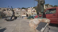 Statue and colourful houses and quayside in Symi Town, Symi Island, Dodecanese Islands, Greek Islands, Greece, Europe