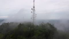Aerial move toward telecommunication tower with low cloud morning