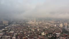 Aerial move over Unesco old heritage building toward Komtar building covered with low fog cloud