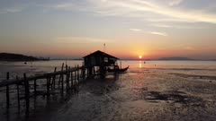 Fly toward a old wooden hut during low tide in sunrise morning