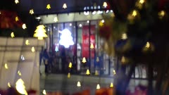 Beautiful defocused christmas tree bokeh flickering in shopping mall. Background people window shopping