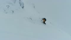 Mountain Climber Using a Pick to Climb a Steep Mountain in the Snow