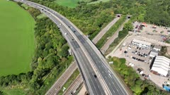 Commuter Train Speeding Under a Motorway in the UK Aerial View