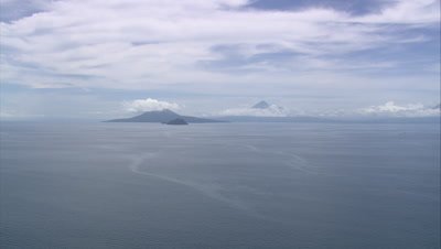 View of island on the horizon with cloud covered mountains